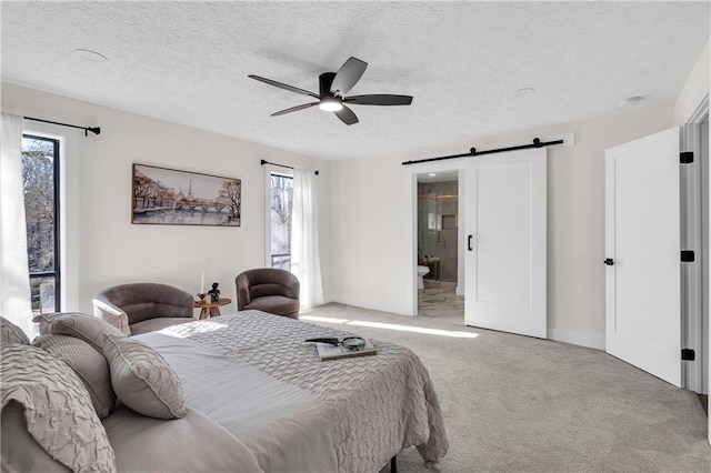 bedroom with multiple windows, carpet flooring, a barn door, baseboards, and a textured ceiling