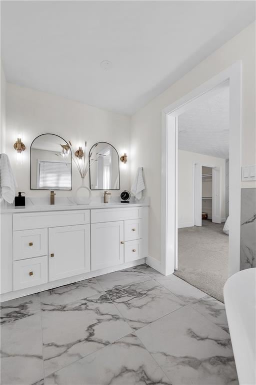 bathroom with double vanity, a soaking tub, marble look tile flooring, and baseboards