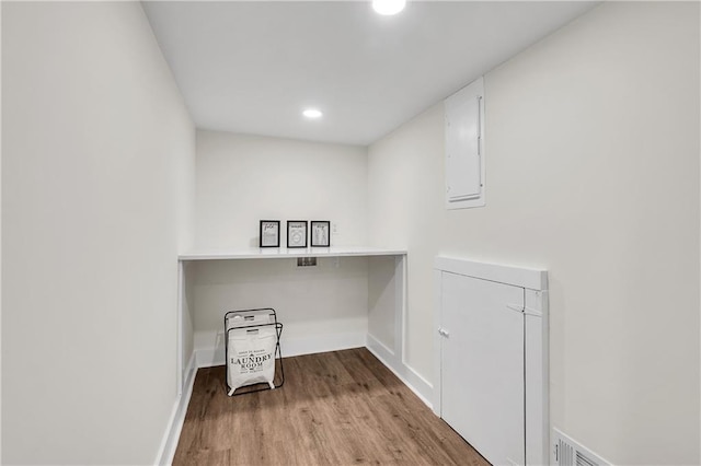 laundry room featuring wood finished floors, baseboards, recessed lighting, and electric panel