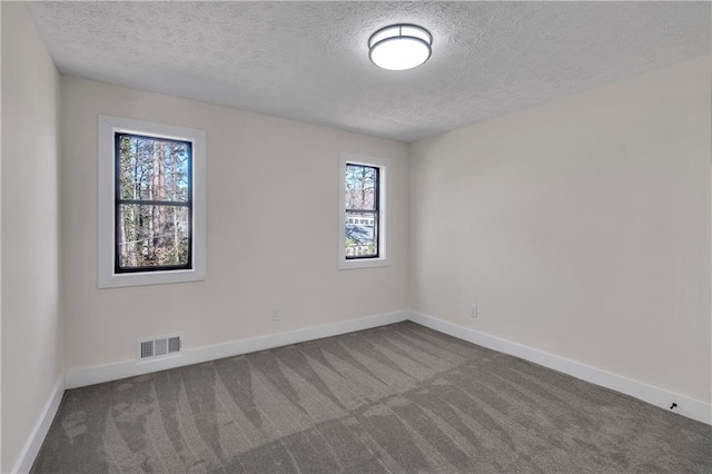 spare room with dark carpet, a textured ceiling, and baseboards