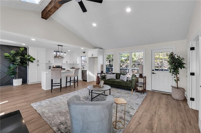 living room with beamed ceiling, a ceiling fan, light wood-style floors, recessed lighting, and high vaulted ceiling