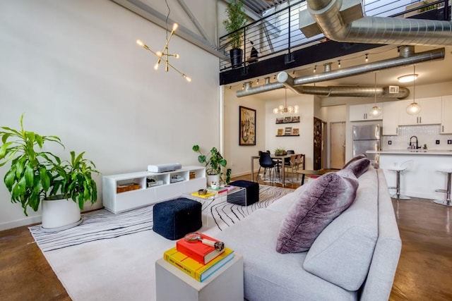 living area featuring baseboards, concrete flooring, a notable chandelier, and a high ceiling