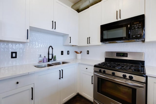 kitchen featuring stainless steel range with gas cooktop, a sink, decorative backsplash, white cabinets, and black microwave