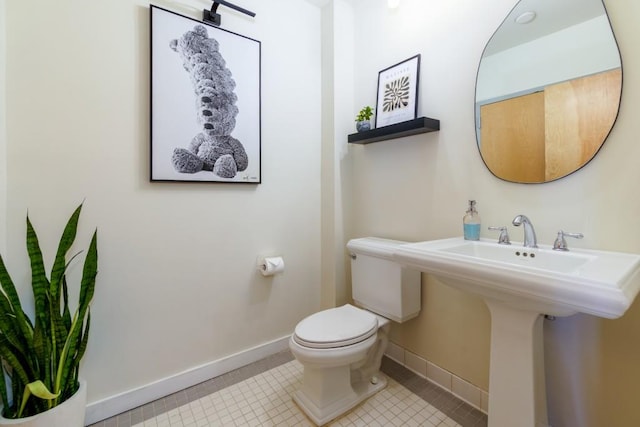 half bathroom featuring tile patterned flooring, toilet, and baseboards