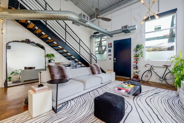 living area with stairway, visible vents, a high ceiling, and ceiling fan