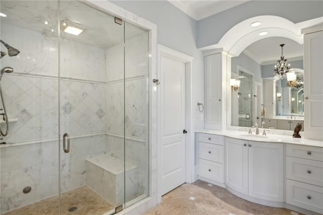full bathroom featuring crown molding, an inviting chandelier, vanity, and a marble finish shower