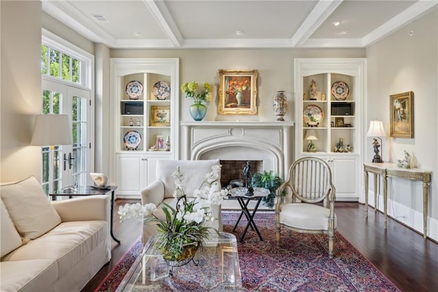 living area with built in features, beam ceiling, a fireplace, visible vents, and wood finished floors