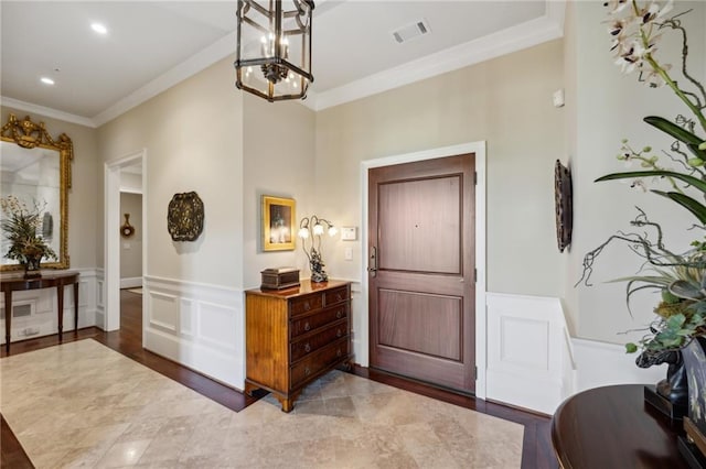 entryway featuring visible vents, crown molding, and wainscoting