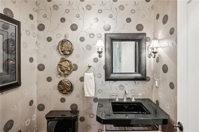 half bathroom with a sink and wallpapered walls