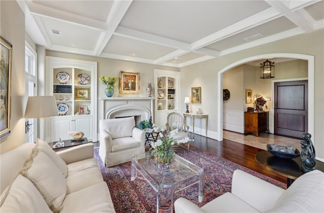 living room with built in features, visible vents, coffered ceiling, arched walkways, and wood finished floors