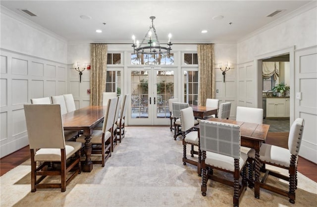 dining room featuring french doors, crown molding, a decorative wall, and visible vents