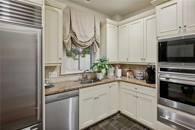 kitchen featuring light stone countertops, a warming drawer, a sink, built in appliances, and backsplash