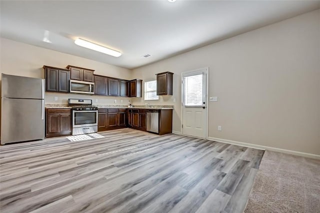 kitchen featuring dark brown cabinetry, sink, stainless steel appliances, and light wood-type flooring