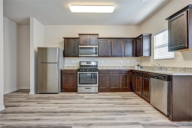 kitchen featuring dark brown cabinets, stainless steel appliances, light hardwood / wood-style flooring, and sink