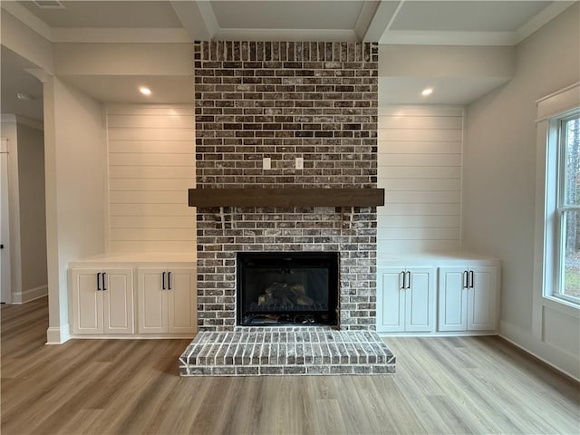 unfurnished living room with beam ceiling, light wood-type flooring, a fireplace, and a wealth of natural light