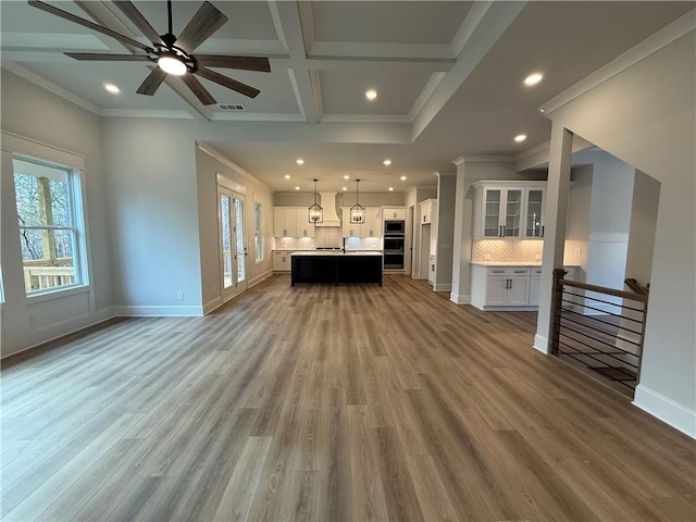 unfurnished living room featuring beam ceiling, ceiling fan, coffered ceiling, crown molding, and wood-type flooring