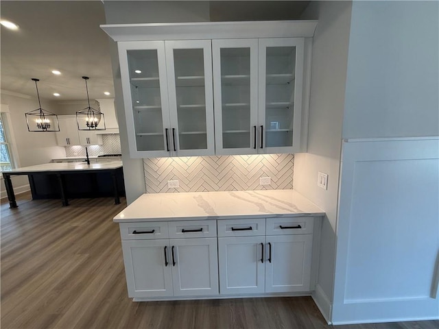 bar featuring decorative backsplash, light stone countertops, dark wood-type flooring, pendant lighting, and white cabinets