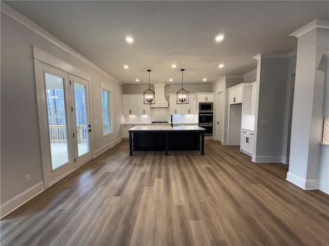 kitchen featuring dark hardwood / wood-style floors, ornamental molding, an island with sink, and stainless steel appliances