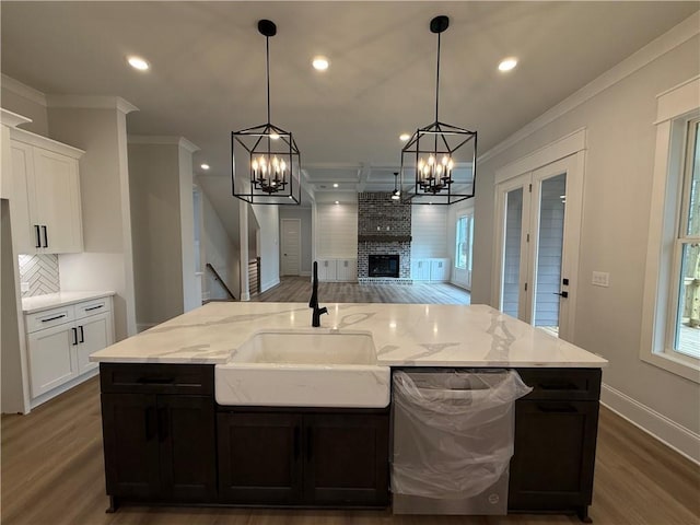 kitchen with dishwasher, white cabinetry, a fireplace, and sink