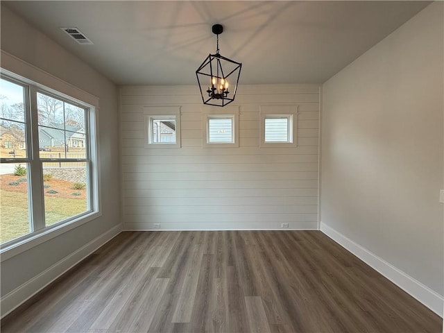 unfurnished dining area featuring hardwood / wood-style floors and a chandelier