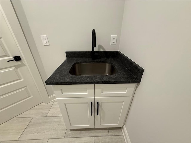 interior space featuring white cabinets, dark stone counters, and sink