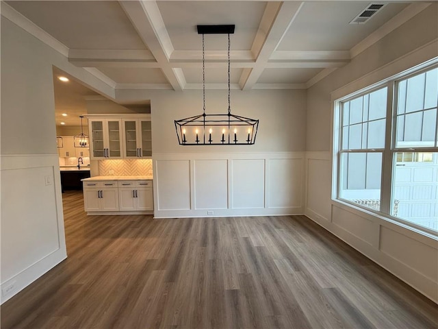 unfurnished dining area featuring wood-type flooring, ornamental molding, coffered ceiling, and beam ceiling