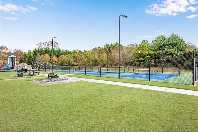 view of tennis court with a playground and a lawn