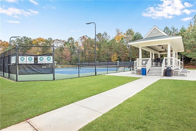 view of sport court with ceiling fan, a deck, and a yard