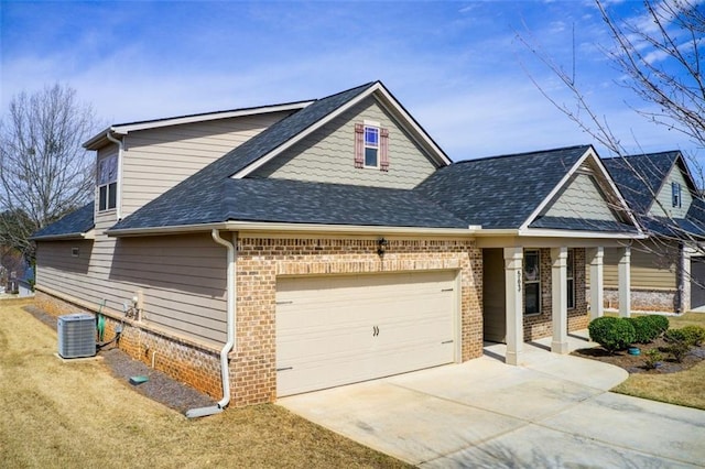 view of front of property featuring brick siding, concrete driveway, roof with shingles, cooling unit, and a garage