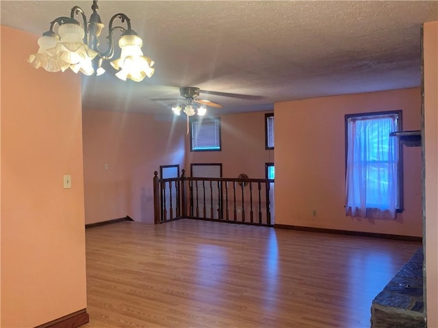 unfurnished room featuring hardwood / wood-style flooring, ceiling fan with notable chandelier, and a textured ceiling