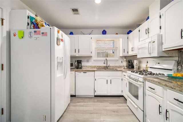 kitchen with white cabinetry, sink, light stone counters, and white appliances