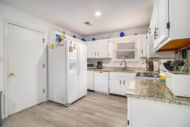 kitchen with white cabinetry, sink, light stone countertops, white appliances, and light hardwood / wood-style flooring