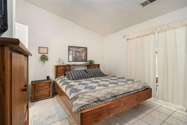 tiled bedroom featuring lofted ceiling and a textured ceiling