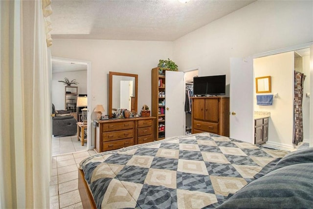 tiled bedroom featuring ensuite bathroom, lofted ceiling, a spacious closet, a textured ceiling, and a closet