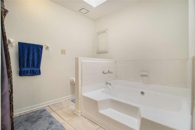 bathroom with a bath, a skylight, and tile patterned flooring