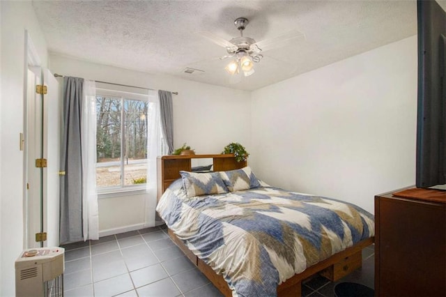 tiled bedroom with a textured ceiling and ceiling fan