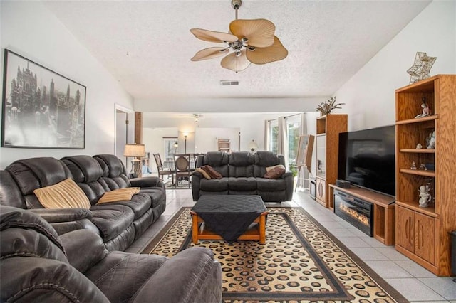 tiled living room with ceiling fan, vaulted ceiling, and a textured ceiling