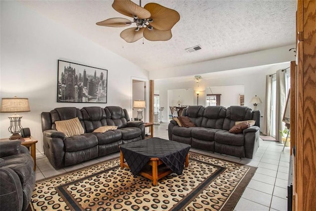 living room featuring ceiling fan, lofted ceiling, a textured ceiling, and light tile patterned floors