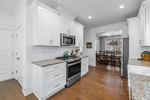 352 Davis St, Monroe, GA 30655 - kitchen featuring appliances with stainless steel finishes, dark wood finished floors, crown molding, white cabinetry, and light stone countertops