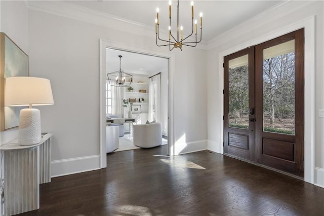 foyer entrance featuring french doors, ornamental molding, dark wood-type flooring, and a notable chandelier