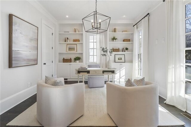 sitting room featuring hardwood / wood-style flooring, ornamental molding, an inviting chandelier, and built in shelves