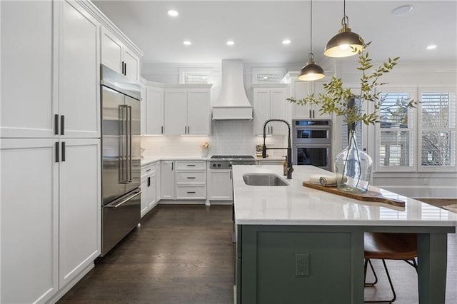 kitchen featuring custom exhaust hood, sink, white cabinets, and stainless steel appliances