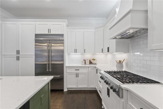 kitchen with appliances with stainless steel finishes, white cabinetry, dark hardwood / wood-style flooring, crown molding, and custom range hood