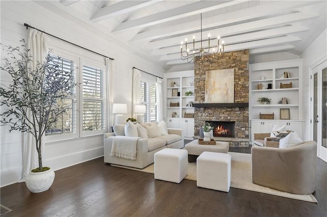 living room with dark hardwood / wood-style floors, a notable chandelier, a fireplace, lofted ceiling with beams, and built in shelves