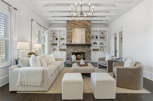 living room with built in shelves, a stone fireplace, an inviting chandelier, lofted ceiling with beams, and dark hardwood / wood-style floors