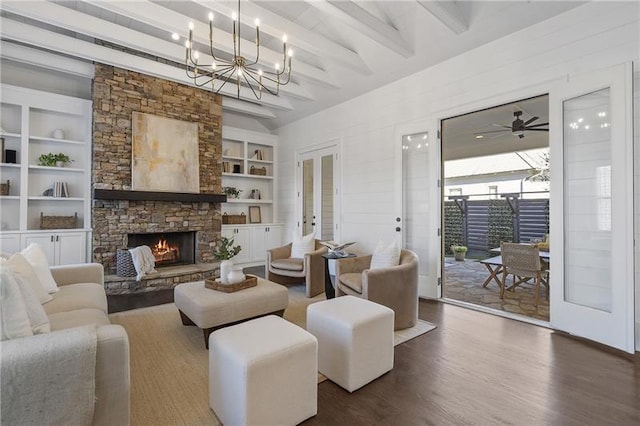 living room with a stone fireplace, beamed ceiling, dark hardwood / wood-style flooring, a notable chandelier, and french doors