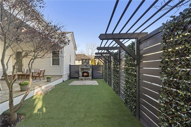 view of yard featuring a pergola, a patio area, and an outdoor stone fireplace