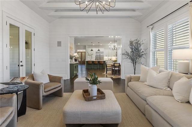 living room with a notable chandelier, vaulted ceiling with beams, french doors, and light wood-type flooring