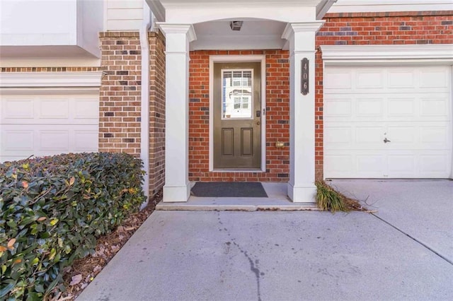 view of exterior entry with brick siding, driveway, and a garage