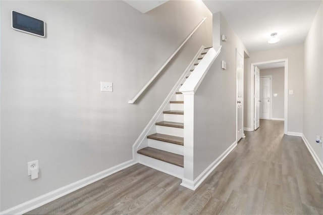 stairway with wood finished floors and baseboards